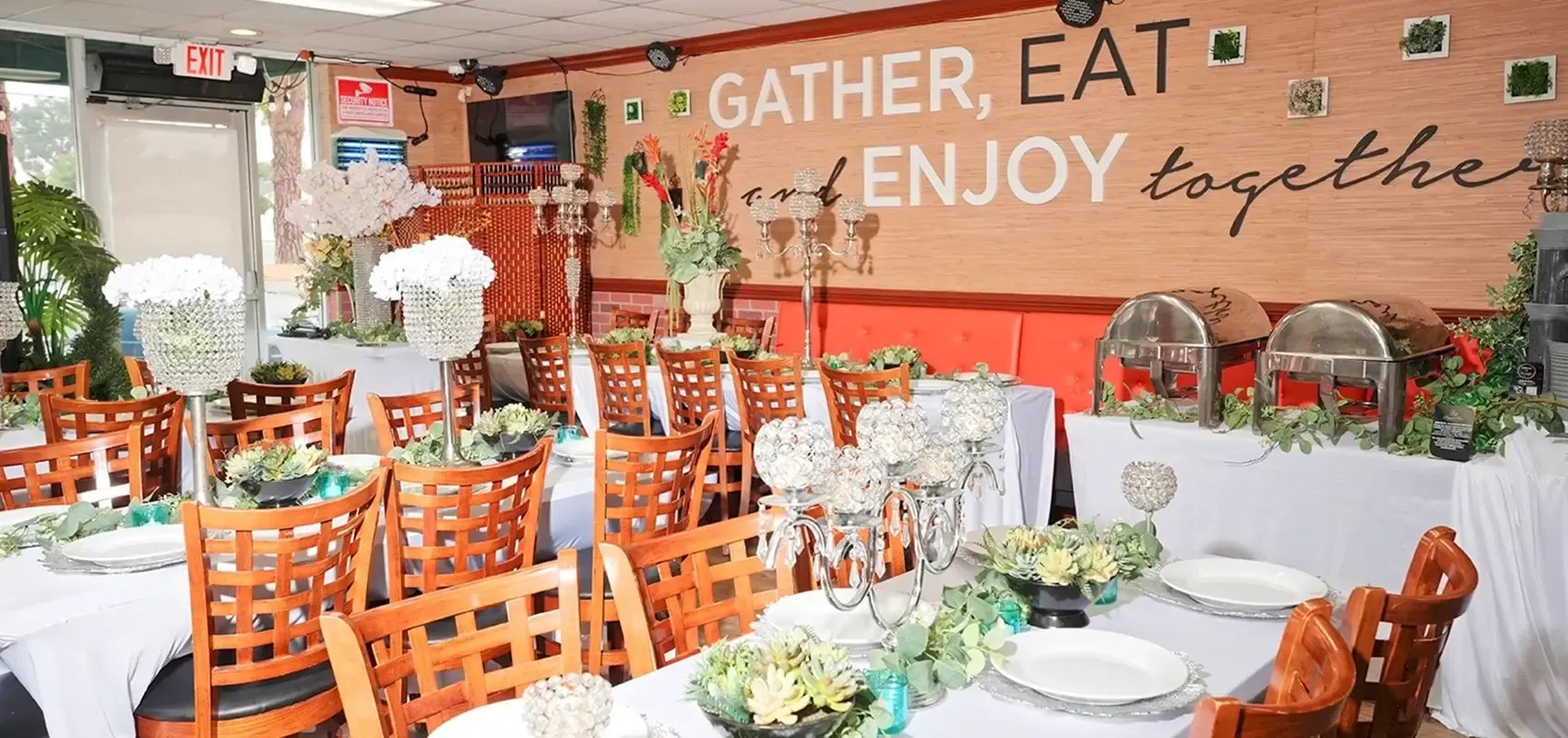Dining room set with tables, candle centerpieces, and a wall reading Gather, Eat and Enjoy together