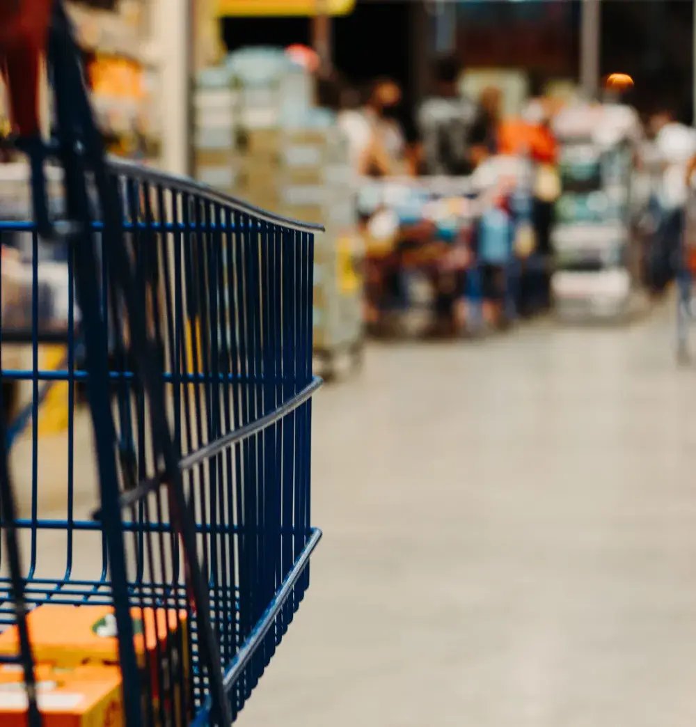 Shopping cart in a busy grocery store aisle